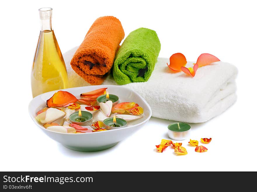 Bowl with rose petals, rose candle and towels on white background. Bowl with rose petals, rose candle and towels on white background