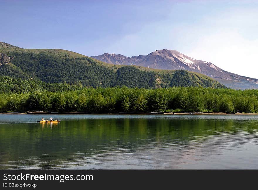 Yellow kayak over the lake with Mount St. Helens National Volcanic Monument on a background. Yellow kayak over the lake with Mount St. Helens National Volcanic Monument on a background