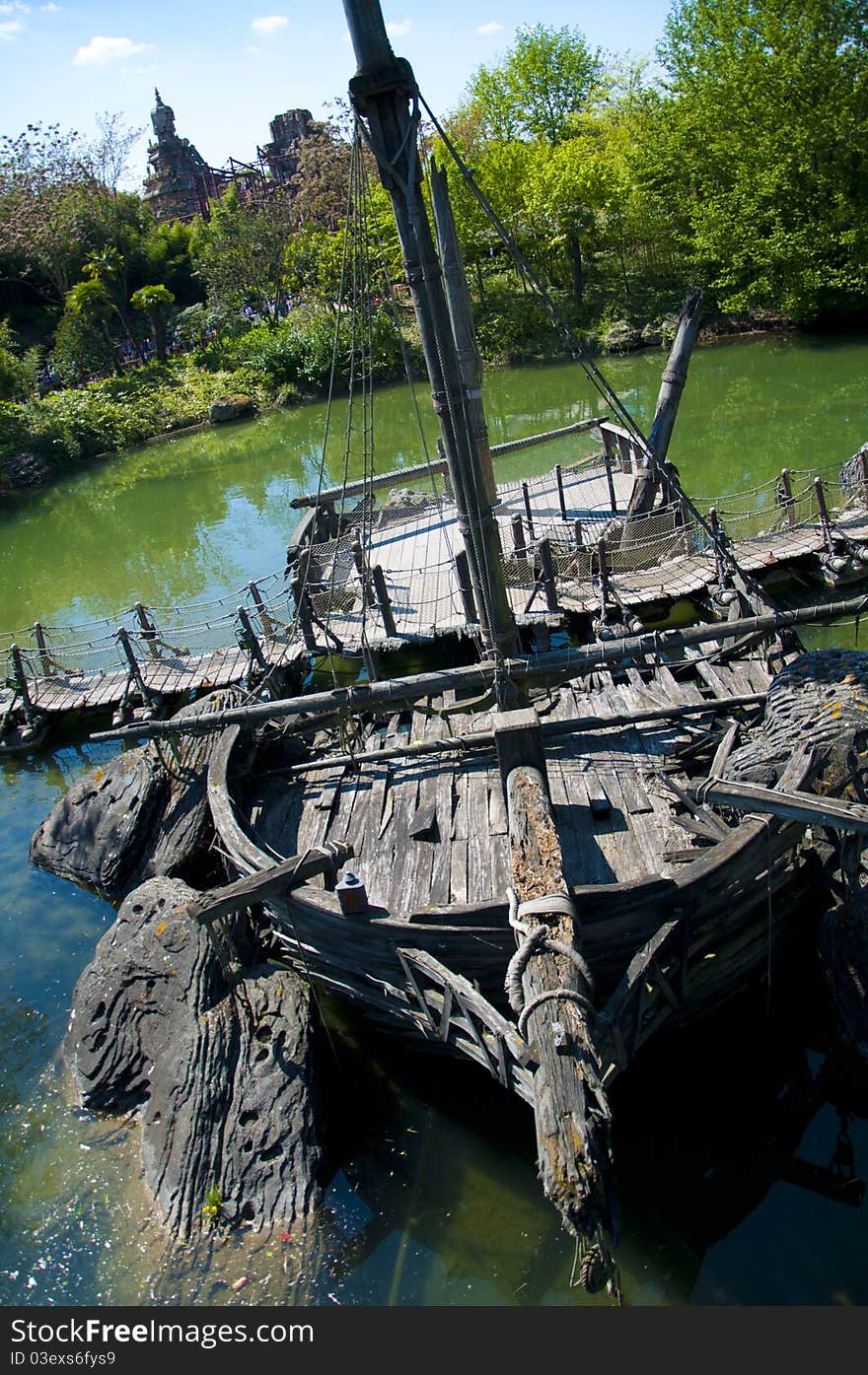 A shipwreck abandoned in a river, now being used to help support a walkbridge