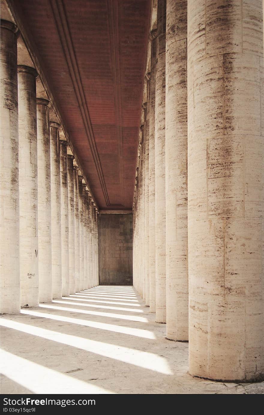 Grey colonnade in perspective with dark ceiling, sunlight and rhythmic shadows. Grey colonnade in perspective with dark ceiling, sunlight and rhythmic shadows