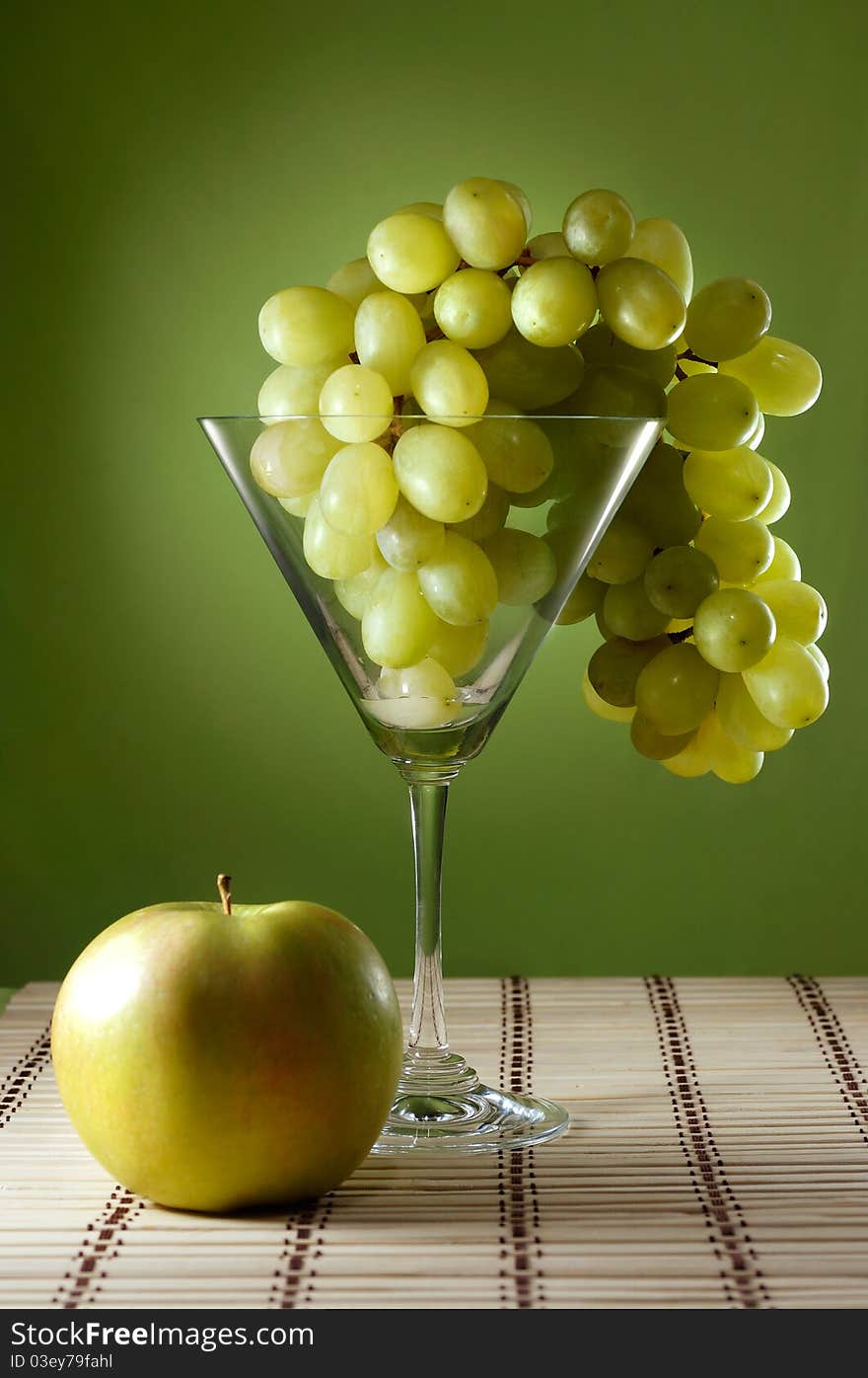 Grapes in a martini glass and an apple food still life. Grapes in a martini glass and an apple food still life