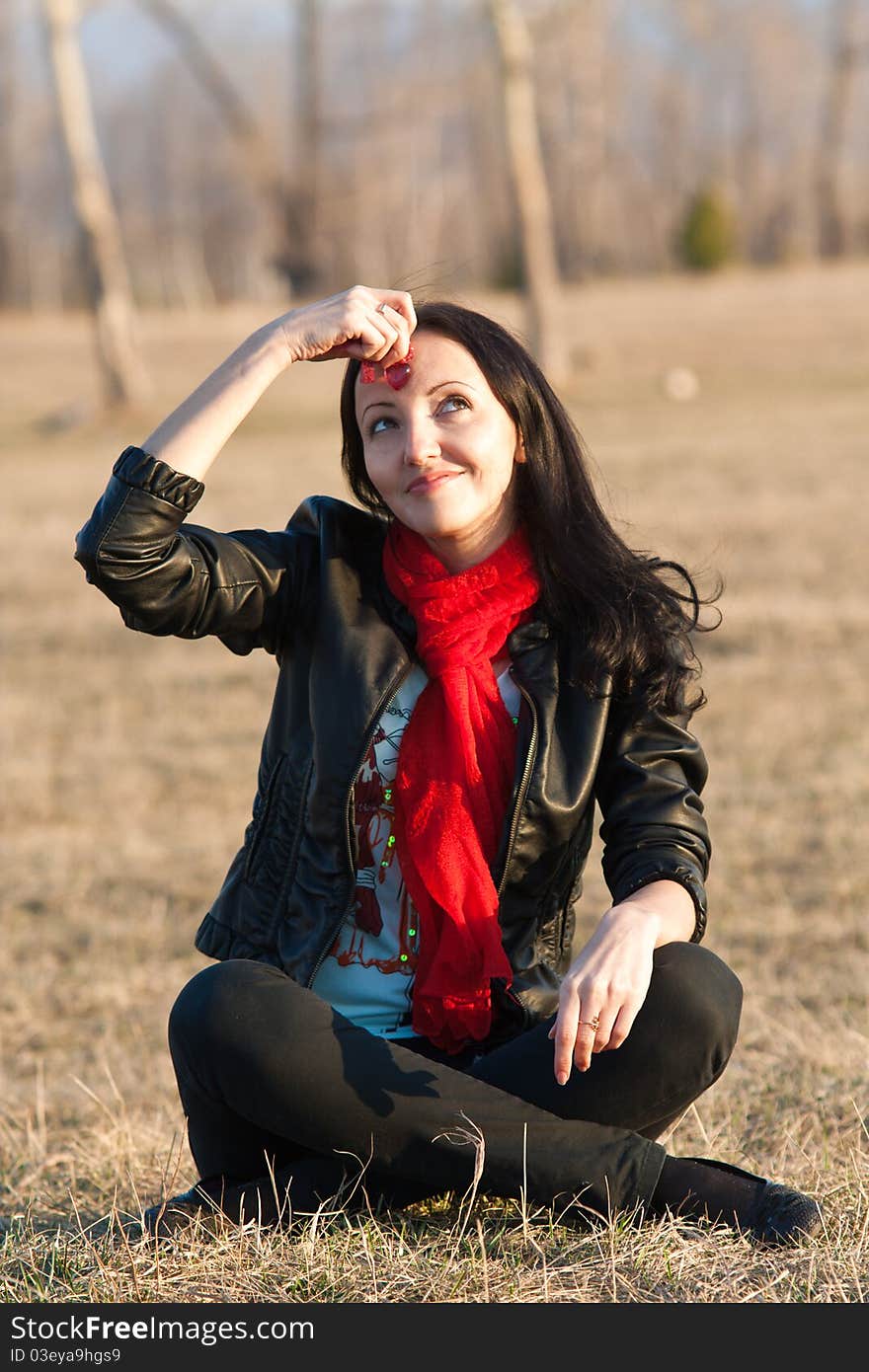 The woman sitting on a grass dreams in the open air