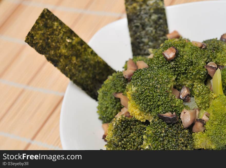 Sumptuous green broccoli dish prepared Asian style and served in white bowl.