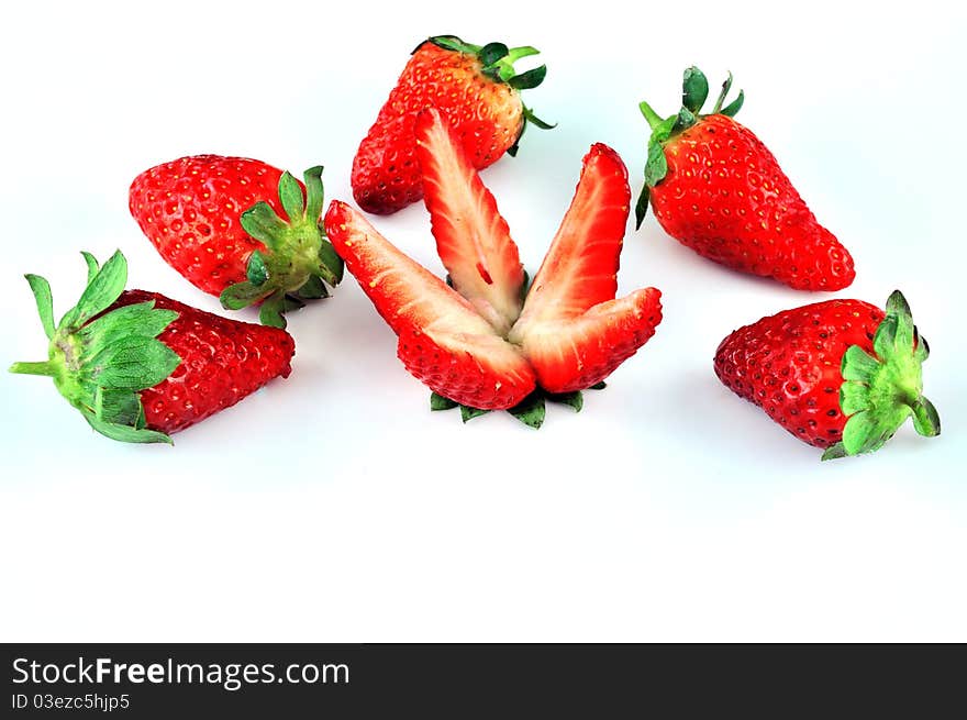 Sliced ​​strawberries and a number of five pieces lying on a white plate. Sliced ​​strawberries and a number of five pieces lying on a white plate