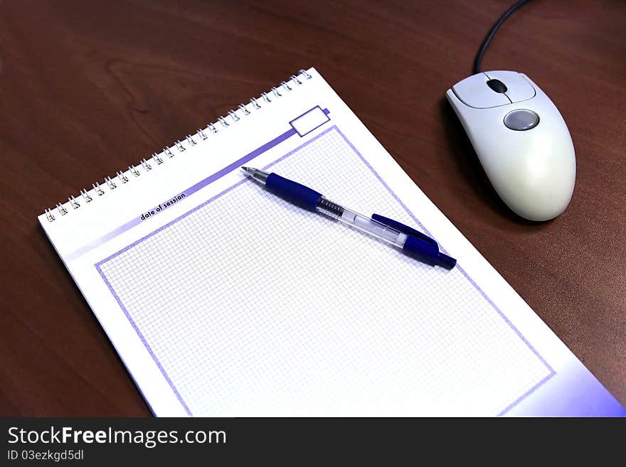 Opened notebook with pen and a computer mouse