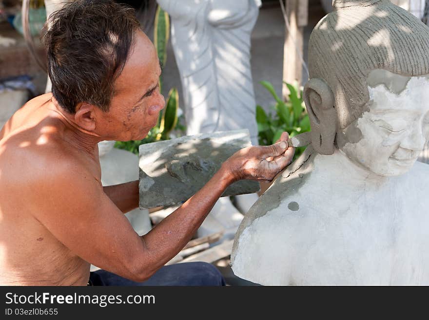 Restore buddhist figure, old Asian man with his craft