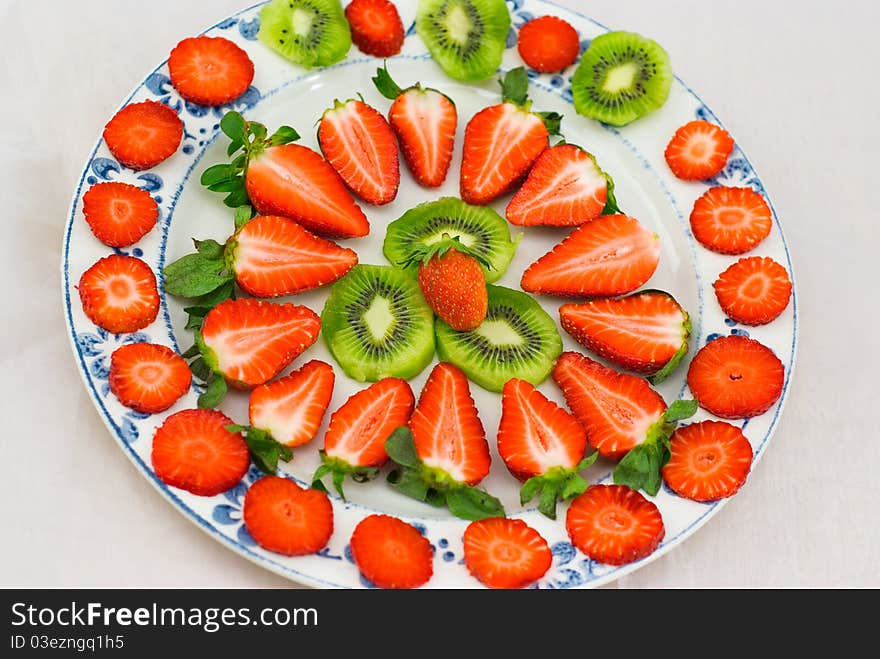 Fresh strawberries and kiwi fruit sliced on a plate on white background