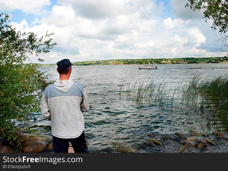 A young man fishing from the lakeshore