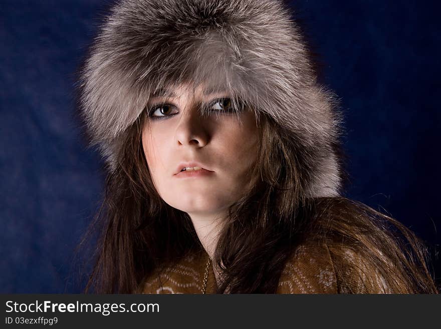 The beautiful mystical women in fur-cap on the dark blue background. The beautiful mystical women in fur-cap on the dark blue background.