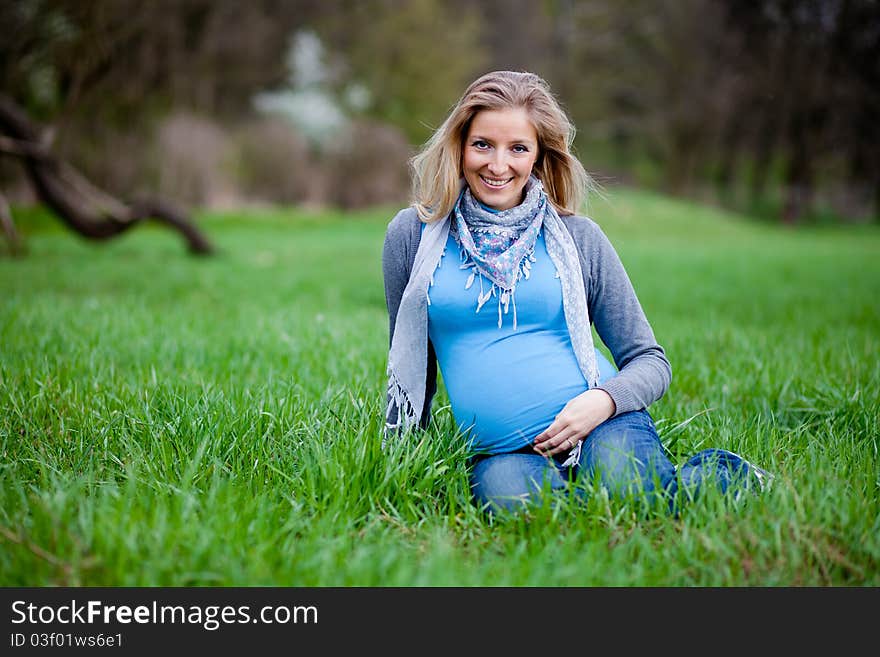 Pregnant woman outdoor in park at spring time