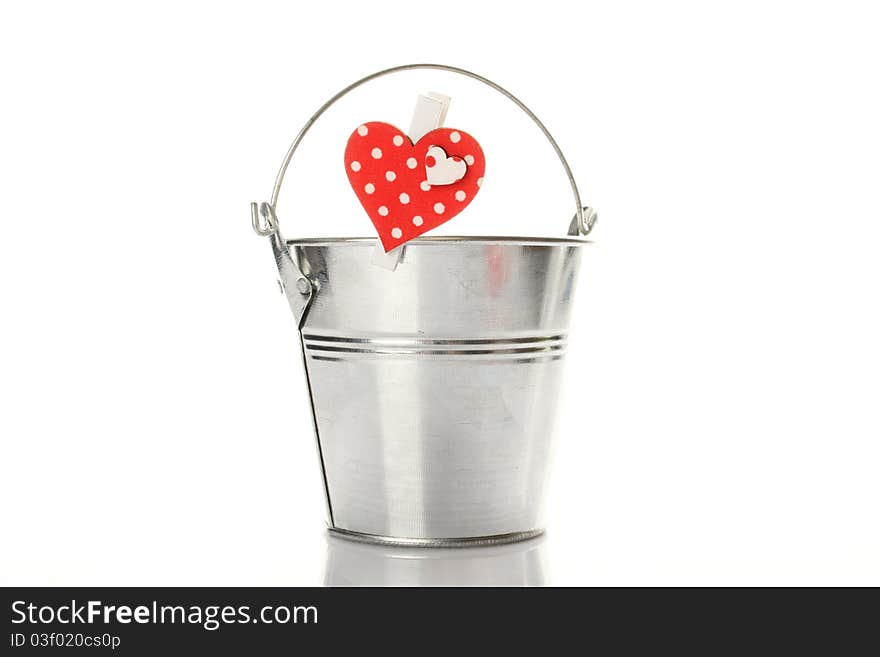 Metal bucket isolated on a white background. On the bucket wooden clothespin with a red heart. Metal bucket isolated on a white background. On the bucket wooden clothespin with a red heart