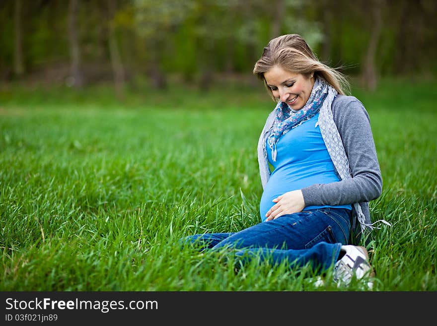 Pregnant woman outdoor in park at spring time