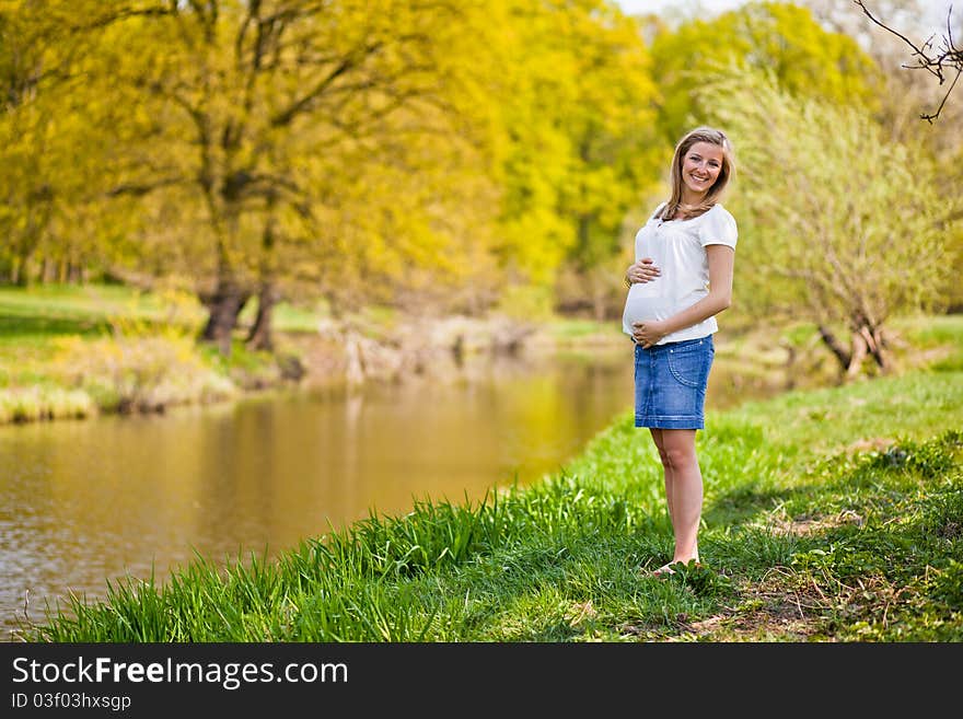 Pregnant woman outdoor in park at spring time