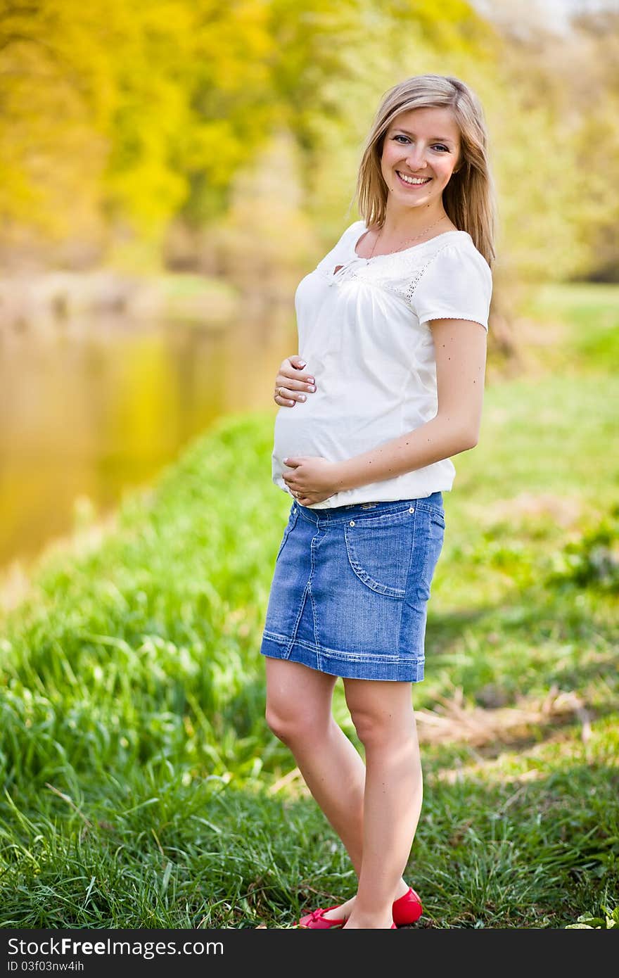 Pregnant woman outdoor in park at spring time