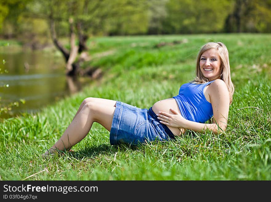 Pregnant woman outdoor in park at spring time