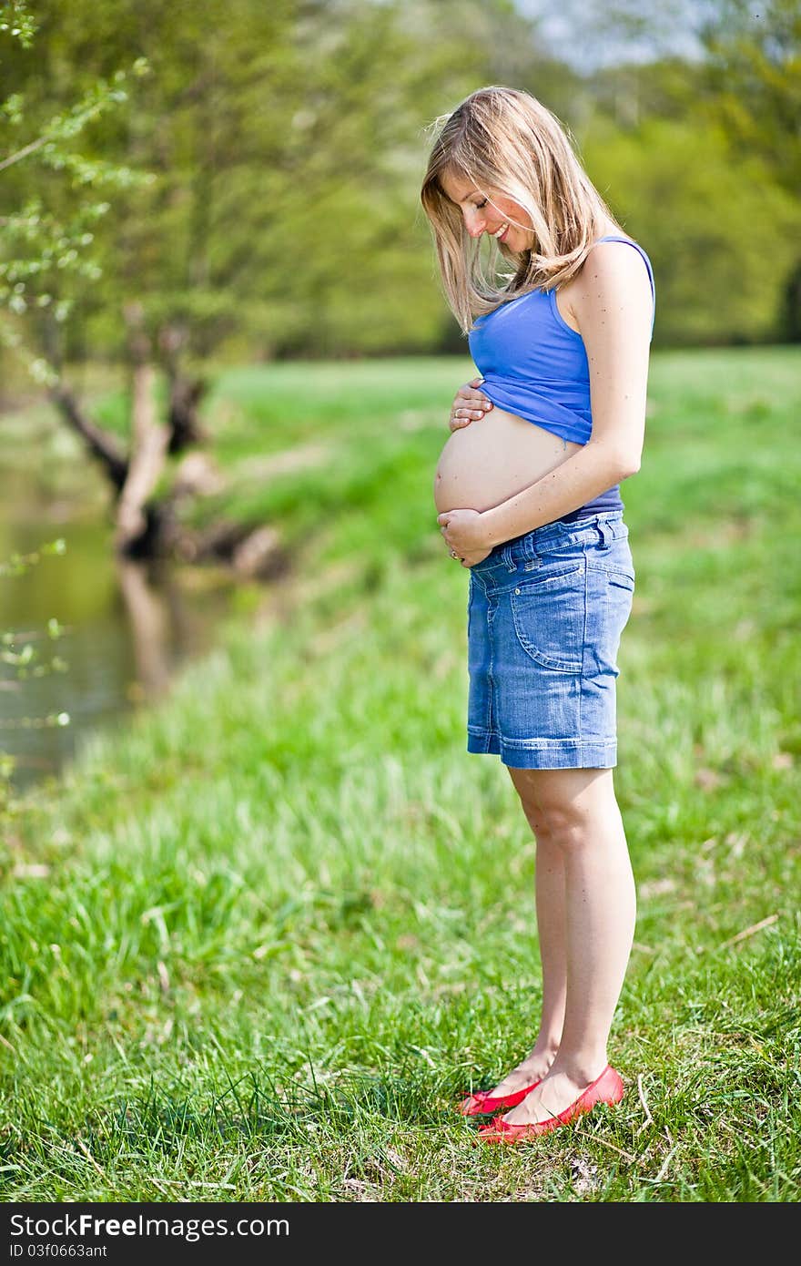 Pregnant woman outdoor in park at spring time