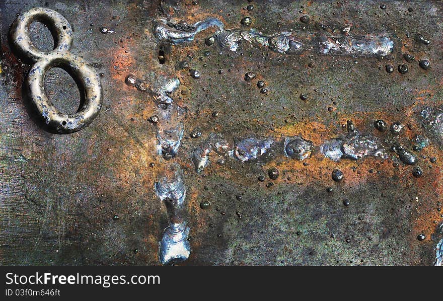 Corrosion and rust, as well as textures only found with weathered, metallic surfaces. A scarred and oxidized number 8 and what appears as the letter F, welded onto the surface, are the dominant elements. Corrosion and rust, as well as textures only found with weathered, metallic surfaces. A scarred and oxidized number 8 and what appears as the letter F, welded onto the surface, are the dominant elements.