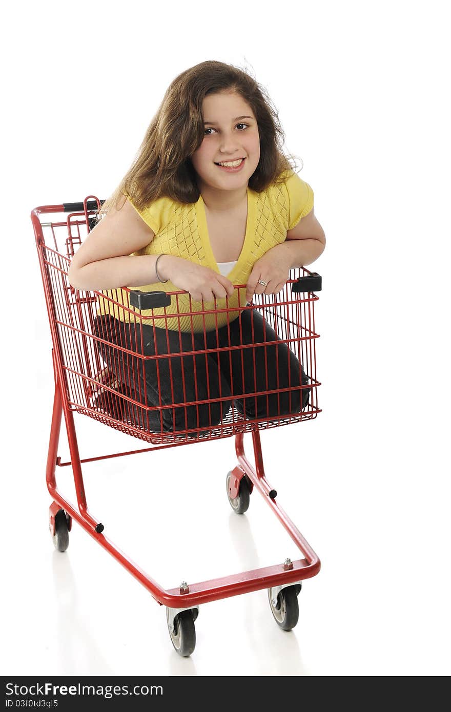 An attractive tween girl riding inside a bright red shopping cart. Isolated on white. An attractive tween girl riding inside a bright red shopping cart. Isolated on white.