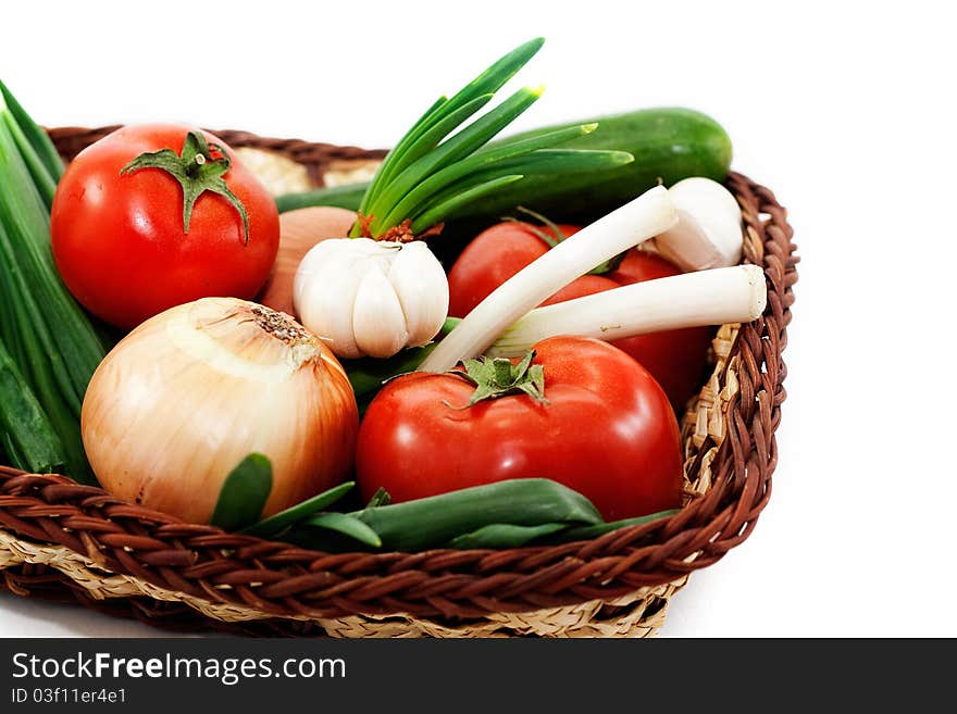 Tomatoes, cucumbers, green onions, garlic in a wicker basket isolated on white background. Tomatoes, cucumbers, green onions, garlic in a wicker basket isolated on white background