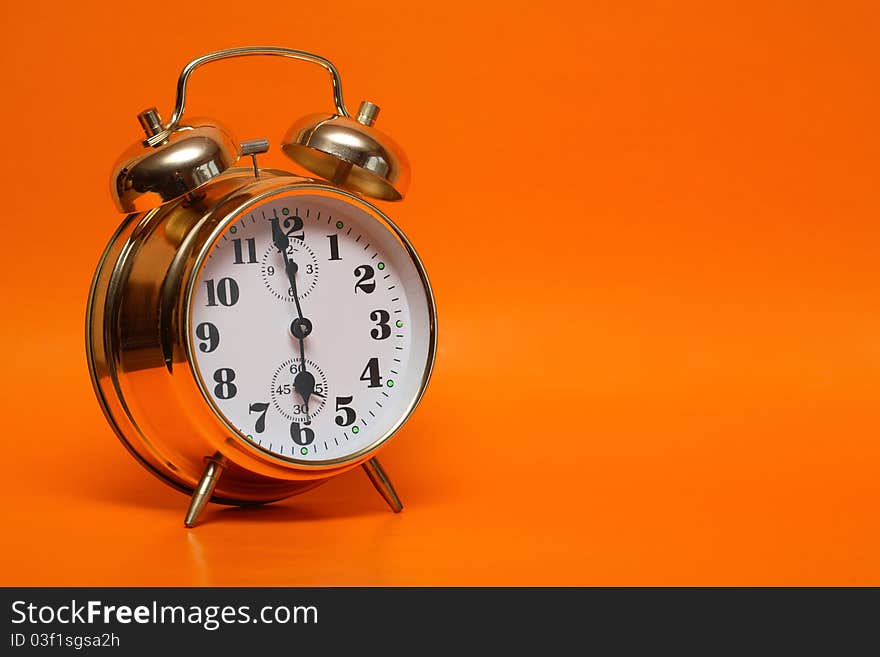 Gold alarm clock standing on nice ginger background with copy space