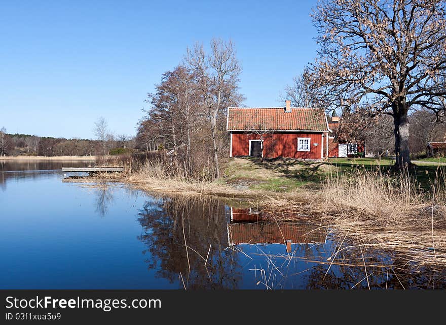 Typiacal red swedish cottage at a lake, reflections in the water. Typiacal red swedish cottage at a lake, reflections in the water.