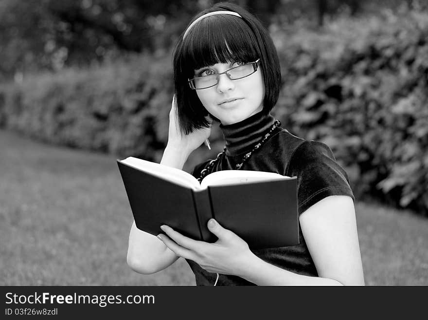 Portrait of attractive young woman with black hair; green nature background