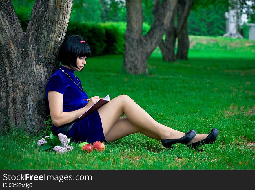 Portrait of attractive young woman with black hair; green nature background