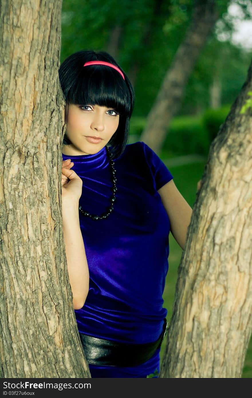 Portrait of attractive young woman with black hair; green nature background