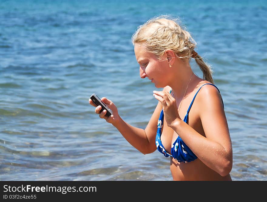 Girl with the phone against the sea