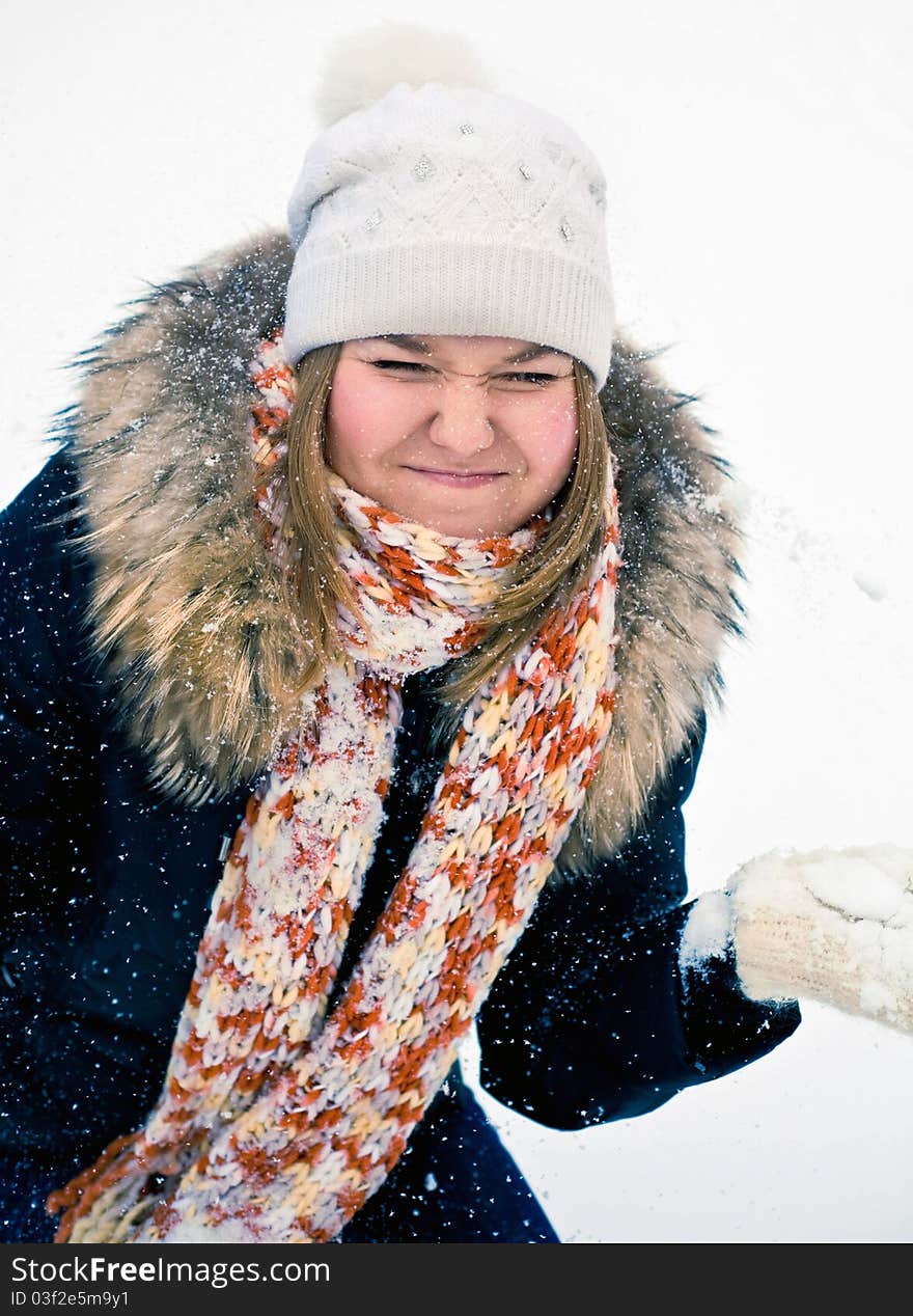 Attractive young woman in wintry coat with large fur head, snowy in background.