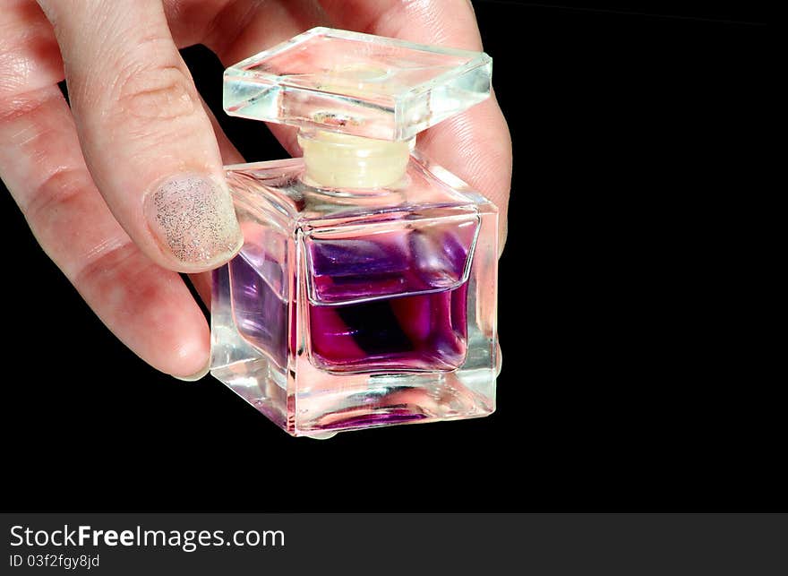 Perfume bottle in a hand on a black background. Perfume bottle in a hand on a black background