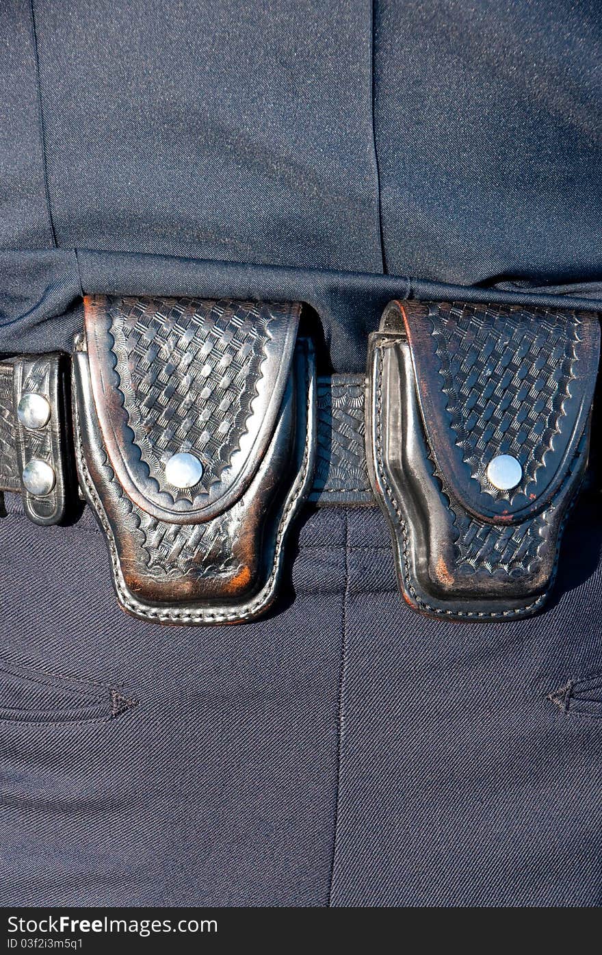 The handcuff cases on the back of a police officer's duty belt.