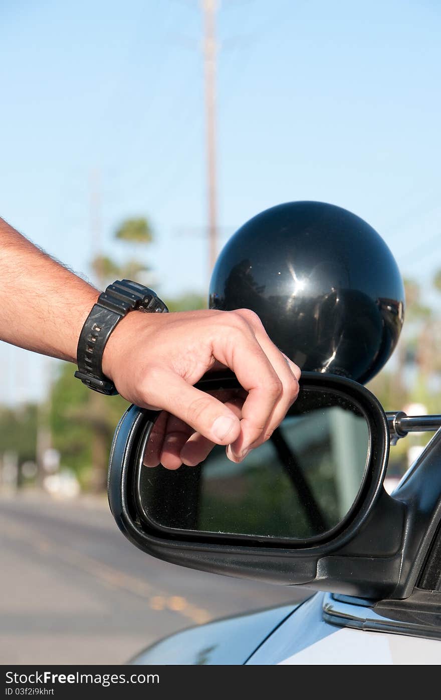 A police officer leaning his hand against the driver side mirror of a police car  . A police officer leaning his hand against the driver side mirror of a police car