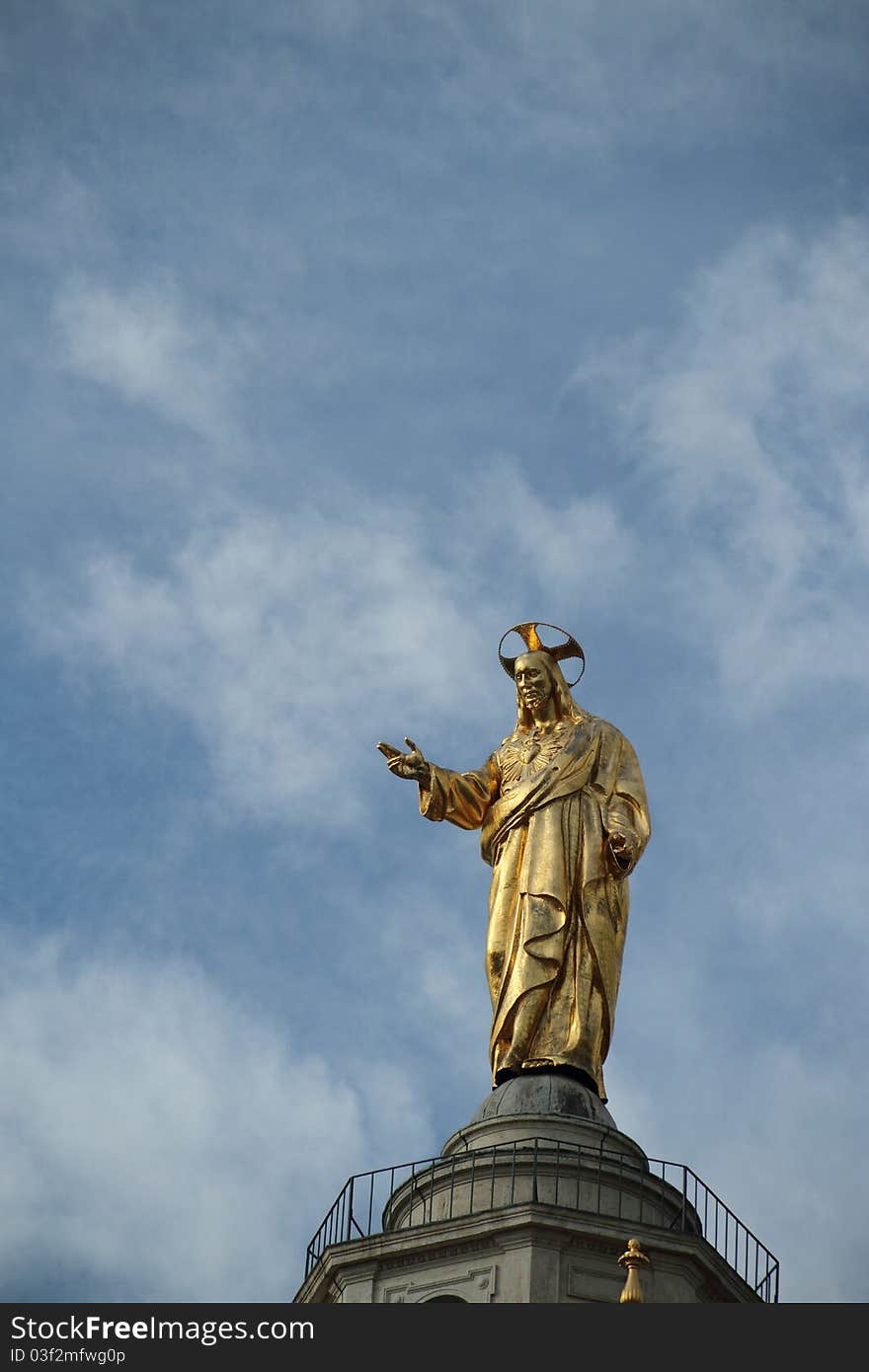 A golden statue of Jesus standing high over the streets of Rome. A golden statue of Jesus standing high over the streets of Rome.