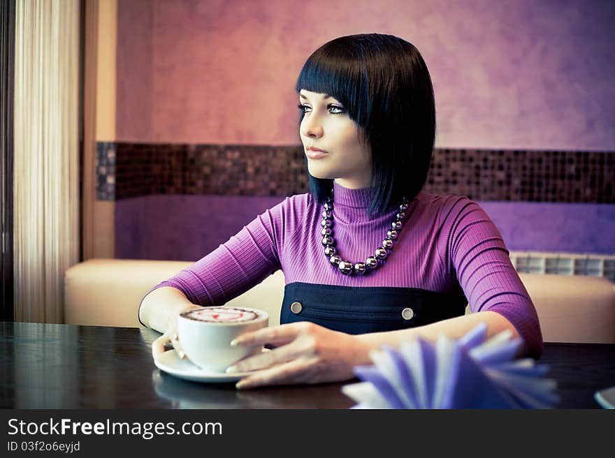 Young woman in cafe with large cap of coffee