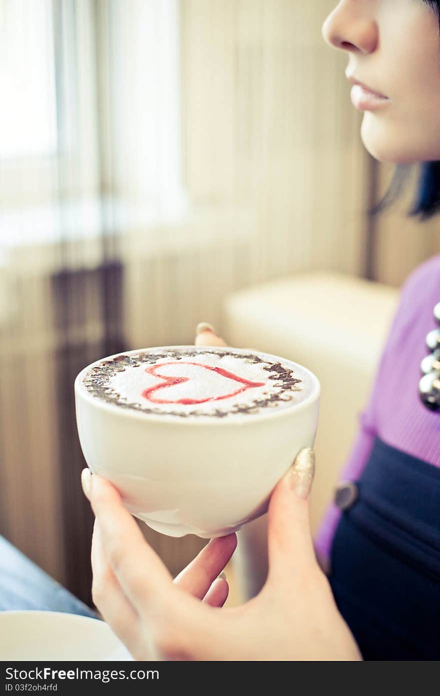 Young woman in cafe with large cap of coffee