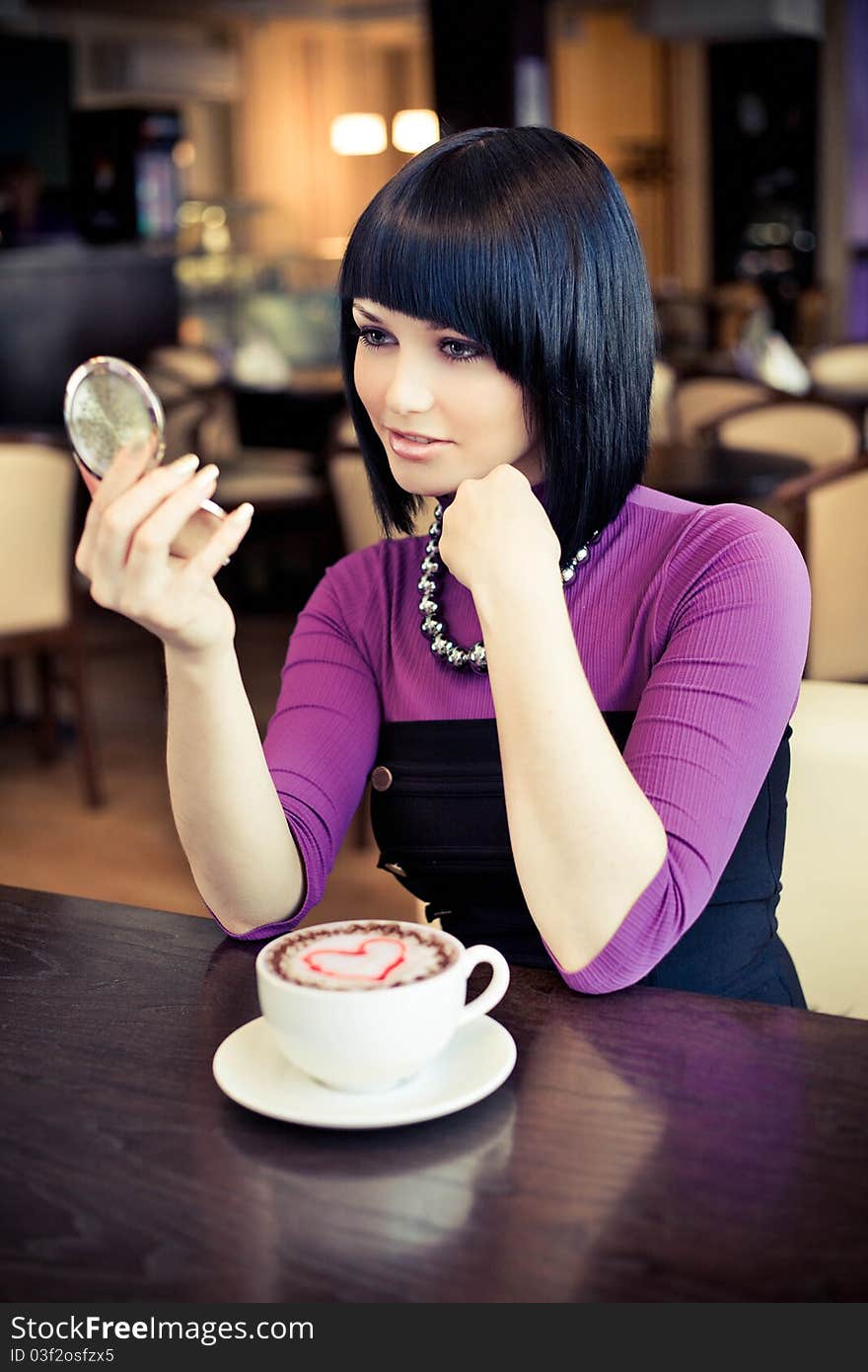 Young woman in cafe with large cap of coffee