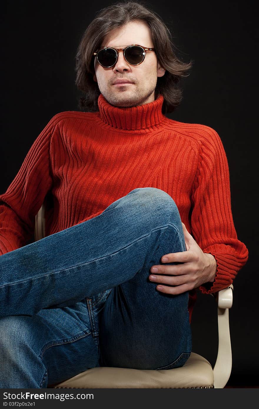 Long hair man wearing sunglasses sitting in armchair