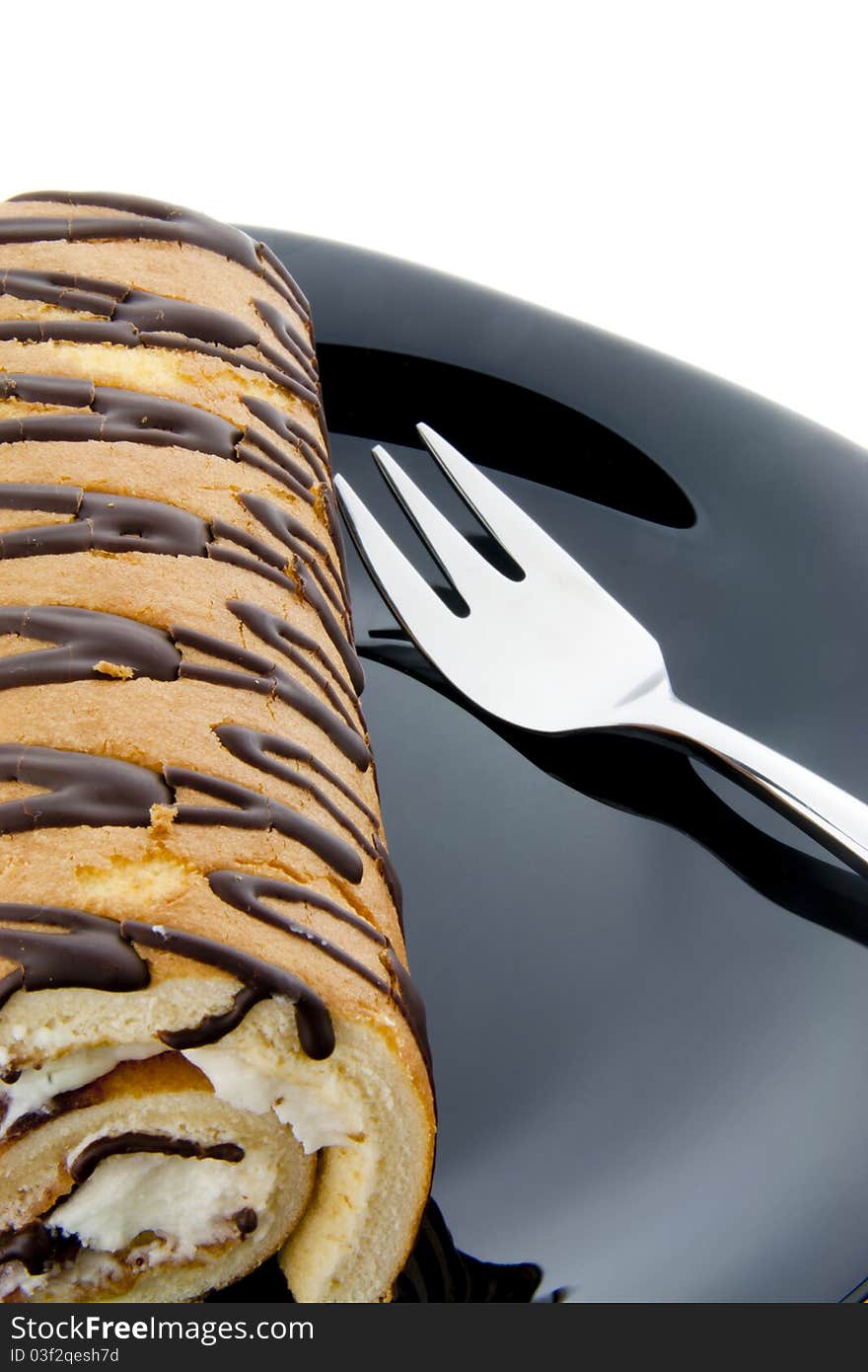 Swiss roll on a black plate with a fork