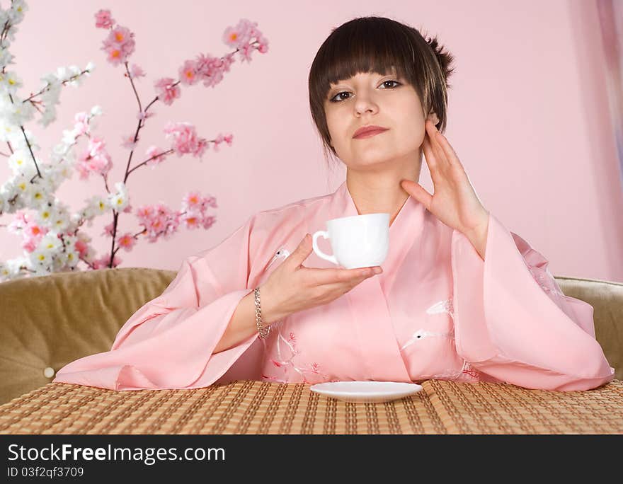 Beautiful girl sitting on a pink