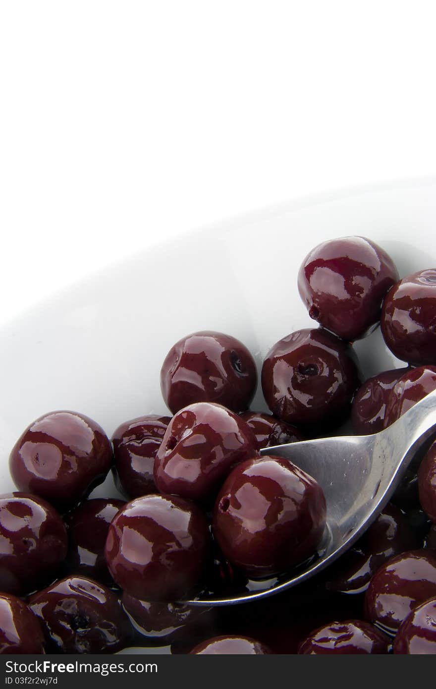 Red cherry on a spoon in a bowl isolated. Red cherry on a spoon in a bowl isolated