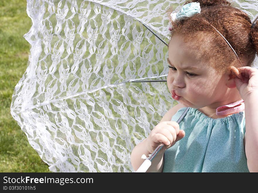 Young girl holding an umbrella during spring time making a funny face. Young girl holding an umbrella during spring time making a funny face.