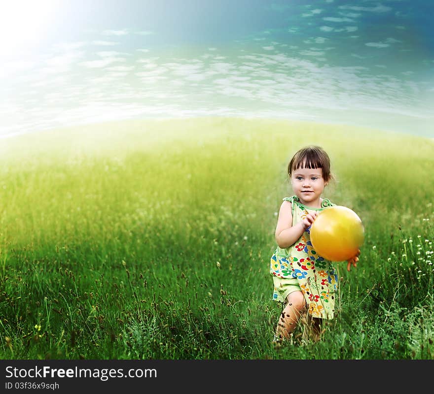 The child playing a ball on the meadow filled in with the sun