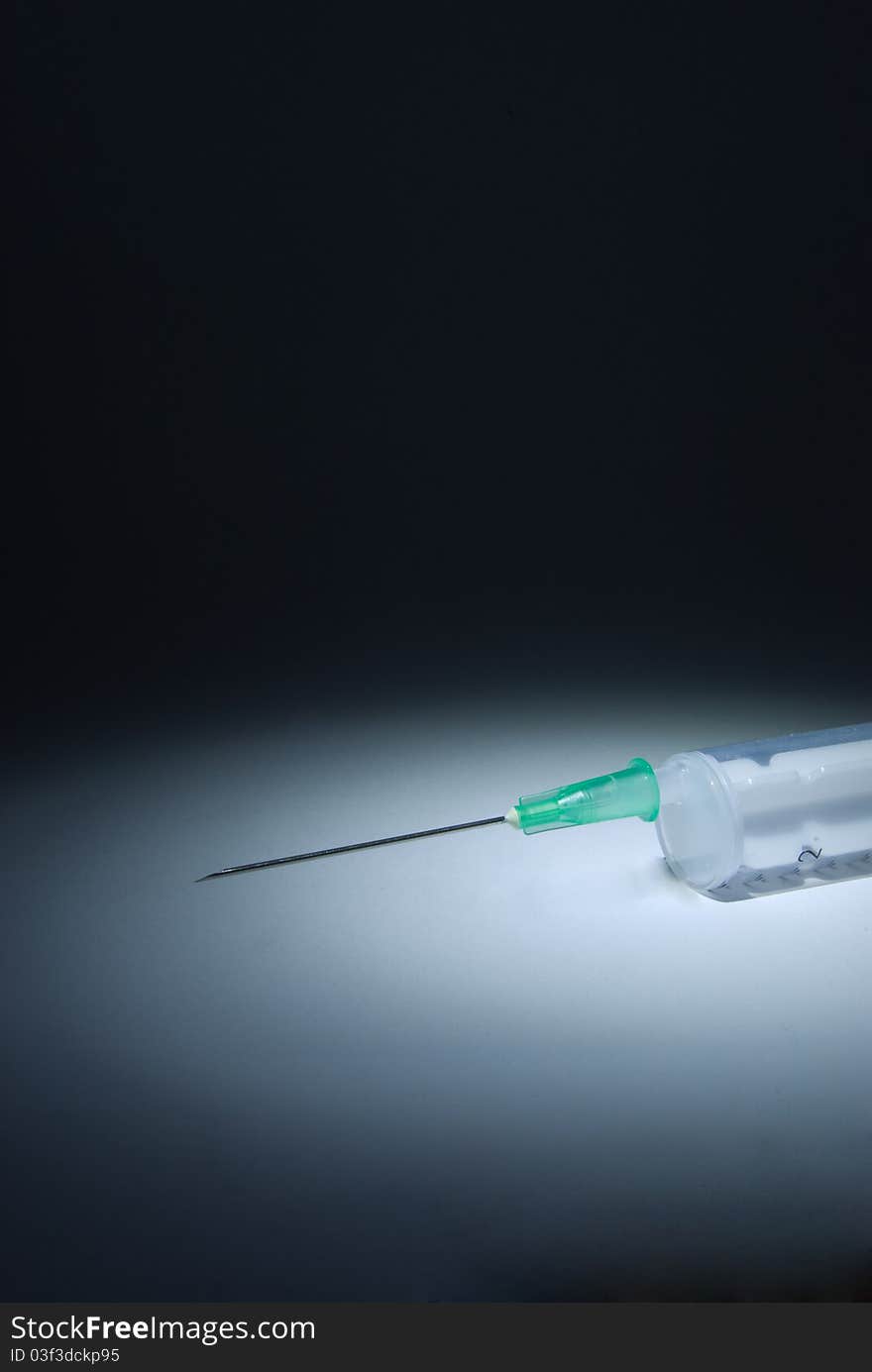 A plastic syringe with hypodermic needle on dark background