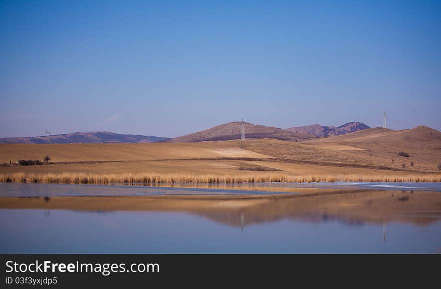 Spring landscape of Horia lake and Macin Mountains in the distance, in Dobrogea region of Romania.