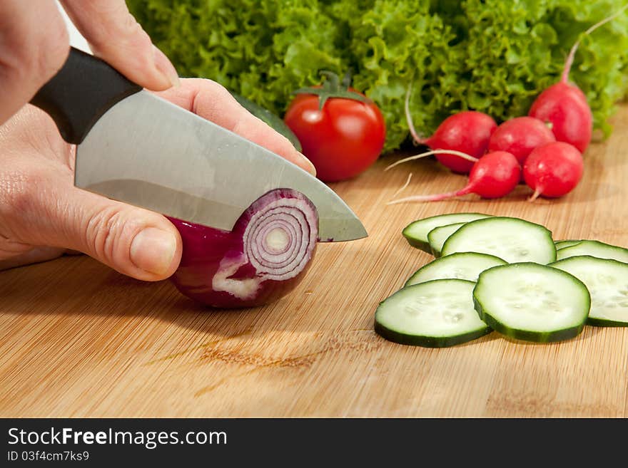 A lady is slicing a red onion. A lady is slicing a red onion