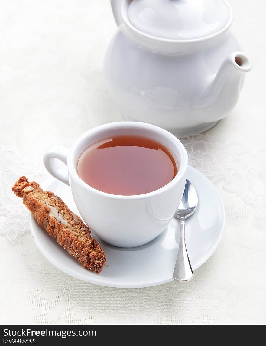 Cup of tea with cookie near the teapot  on white table