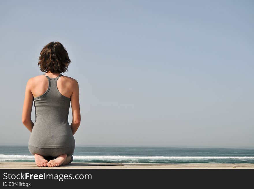 Image of the young woman sitting and relaxing on the beach and looking at the ocean. Image of the young woman sitting and relaxing on the beach and looking at the ocean