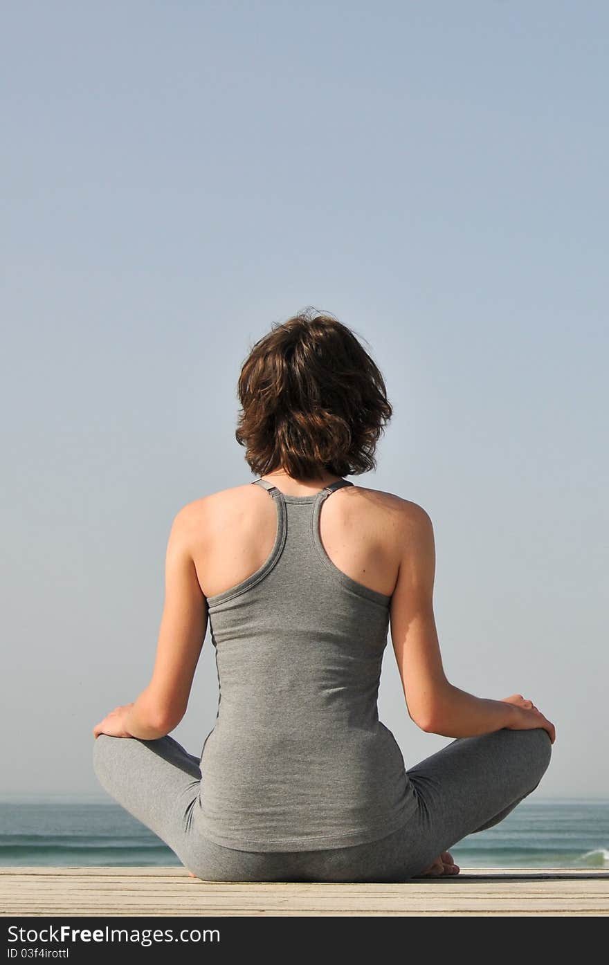 Young woman meditating on the beach