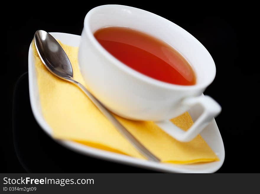 Tea cup and tea spoon on black background